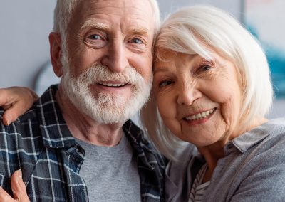 Smiling grey haired couple leaning their heads together
